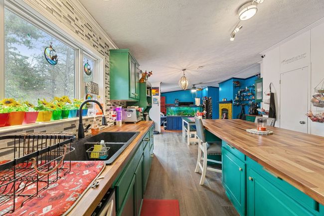 Kitchen featuring wood counters, dark wood-style LVP flooring, open to dining area and family room | Image 9