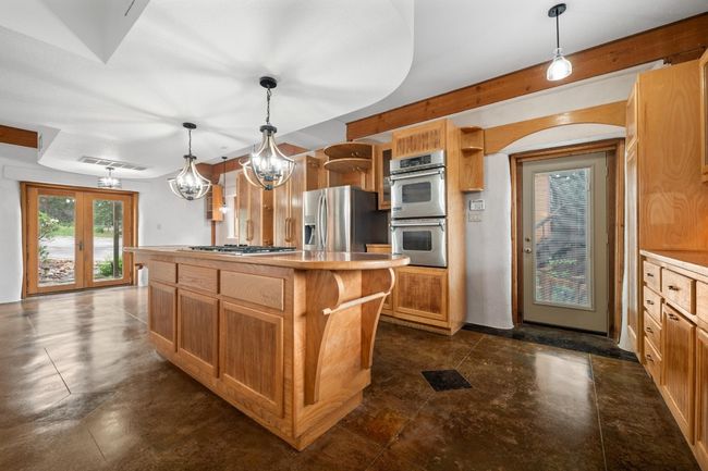 Kitchen with appliances with stainless steel finishes, open shelves, a center island, and decorative light fixtures | Image 6