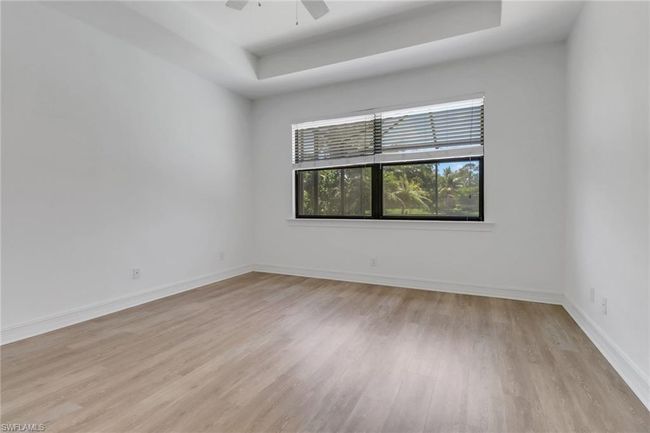 Empty room featuring a raised ceiling, light wood-type flooring, baseboards, and a ceiling fan | Image 17