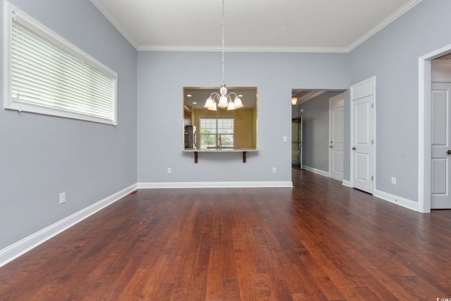 Unfurnished room with dark wood-type flooring, baseboards, a notable chandelier, and crown​​‌​​​​‌​​‌‌​‌‌​​​‌‌​​‌‌​‌​​​​​‌ molding | Image 14