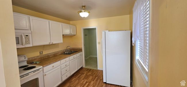 Kitchen with hardwood / wood-style floors, white cabinets, white appliances, and sink | Image 15