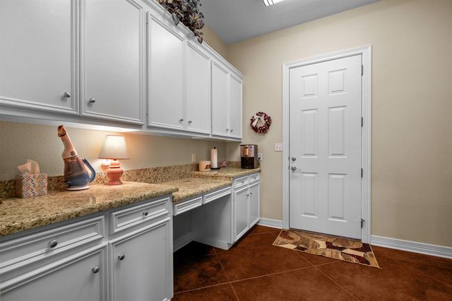 White shaker cabinets, a granite landing counter, and desk nook flank the exterior door—perfect for organizing gear. | Image 19