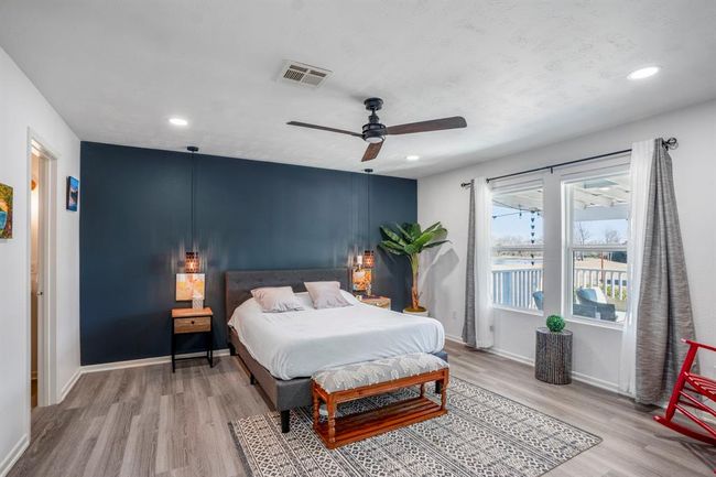 The primary suite offers a spacious retreat with abundant natural light, a bold accent wall, and peaceful views of the property. | Image 18