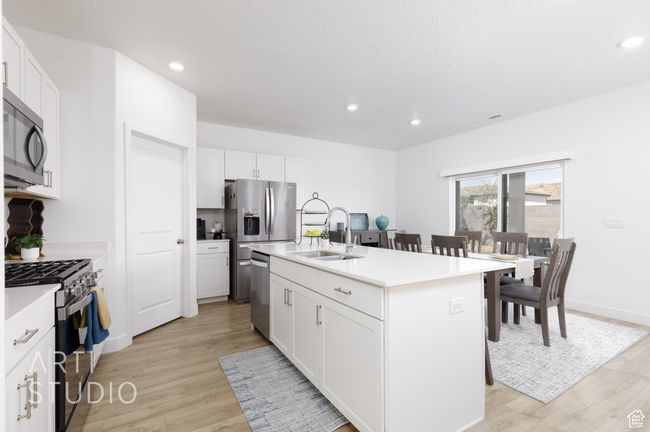 Kitchen featuring a sink, white cabinets, light wood-style flooring, and stainless steel appliances | Image 18
