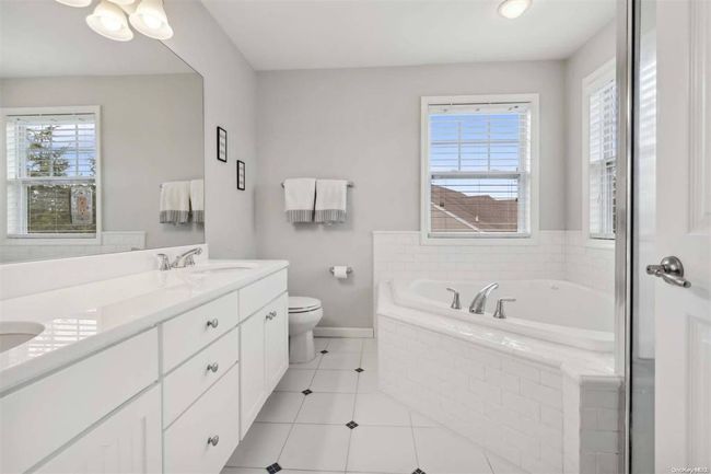 Full bath featuring a bath, toilet, double vanity, baseboards, and tile patterned floors | Image 15