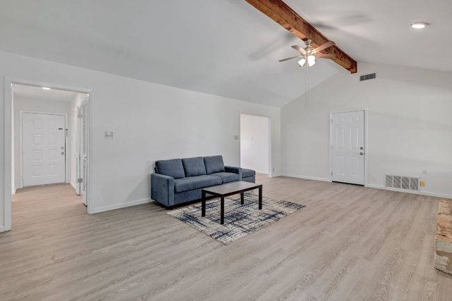 Living room with light wood finished floors, a ceiling fan, and baseboards | Image 5