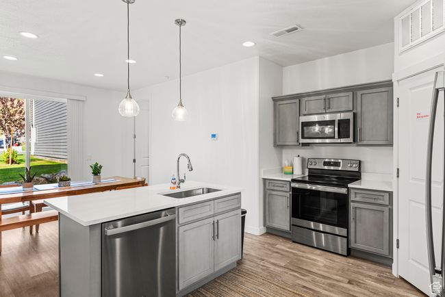 Kitchen with visible vents, gray cabinetry, light wood-type flooring, appliances with stainless steel finishes, and a sink | Image 5