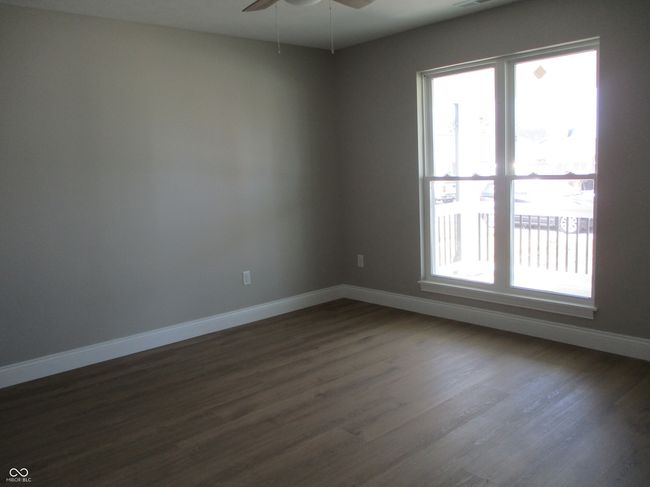 empty room with a ceiling fan, dark wood-style floors, a healthy amount of sunlight, and baseboards | Image 11
