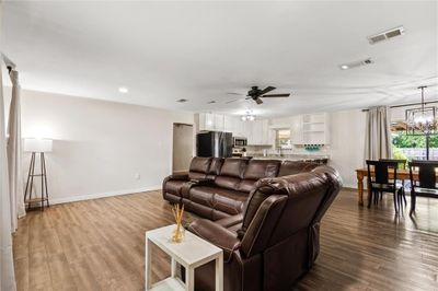 Living room featuring ceiling fan with notable chandelier, wood-type flooring, and a healthy amount of sunlight | Image 3