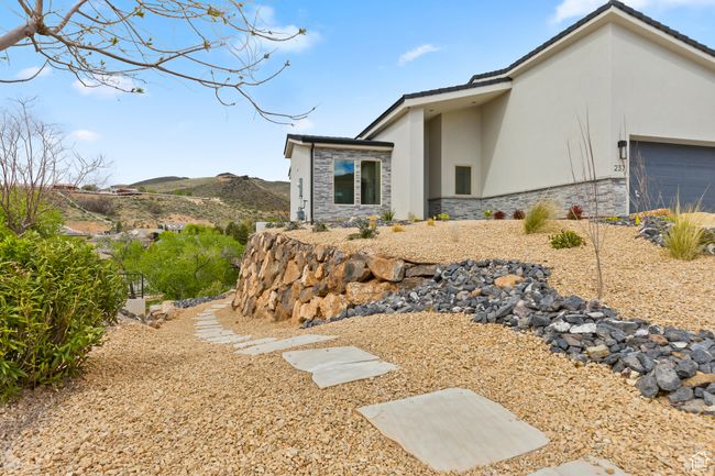 View of property exterior with a mountain view, stucco siding, stone siding, and a garage | Image 13
