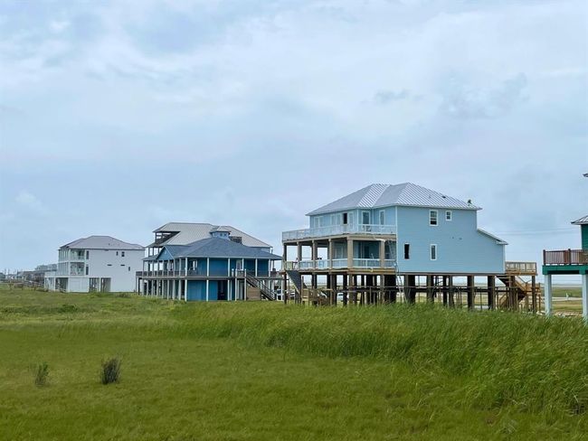 et back on one of the deepest beachfront lots in the community, this angle reveals the home’s impressive 2-story design, screened-in patio, and tiered decking system—all perfectly positioned to maximize Gulf breezes and unobstructed views. | Image 8