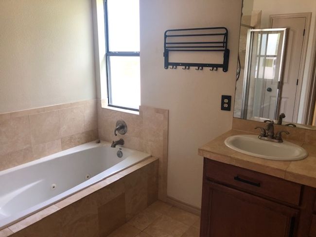 Bathroom with a jetted tub, vanity, a stall shower, and tile patterned floors | Image 8