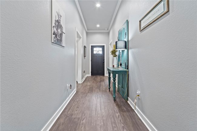 Doorway featuring a textured wall, dark wood finished floors, baseboards, ornamental molding, and recessed lighting | Image 9