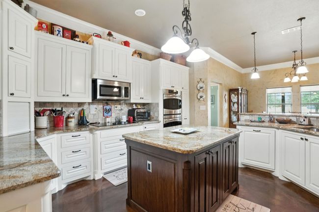 Kitchen with crown molding, white cabinets, finished concrete floors, backsplash, and appliances with stainless steel finishes | Image 10
