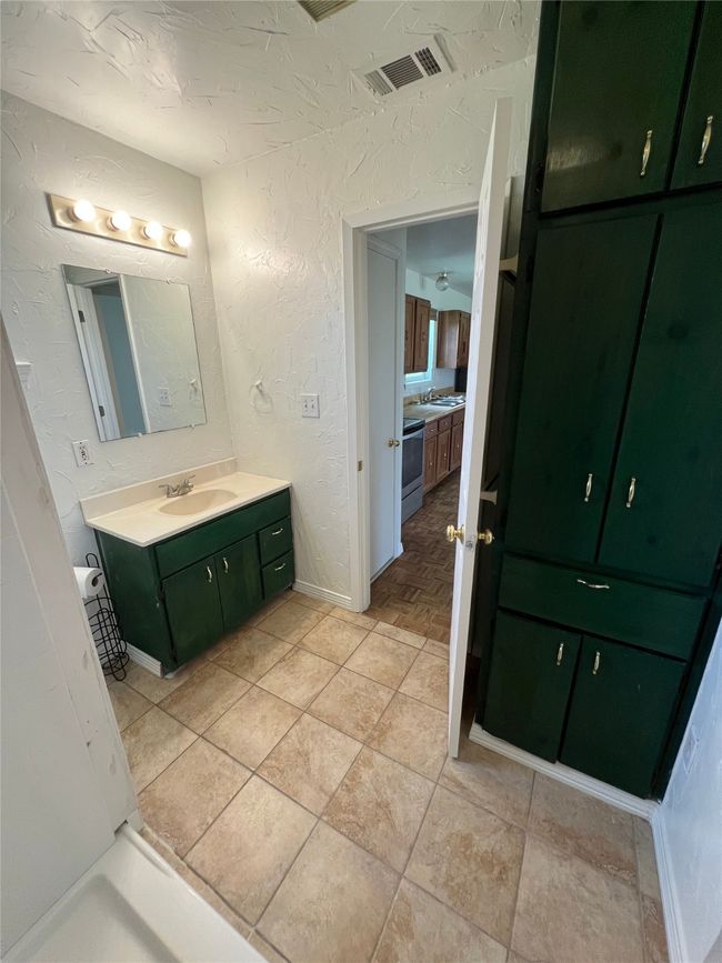 Bathroom featuring a textured wall and vanity | Image 9