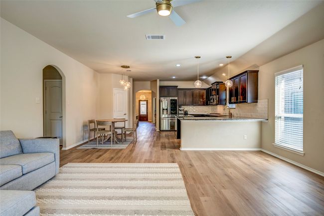 Living room featuring visible vents, arched walkways, light wood-type flooring, a ceiling fan, and vaulted ceiling | Image 22