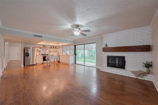 Kitchen is open to the family room with shiplap wall and fireplace with large wood mantle | Image 10