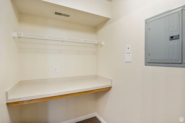 Walk in closet featuring electric panel, built in desk, and dark wood-style flooring | Image 12