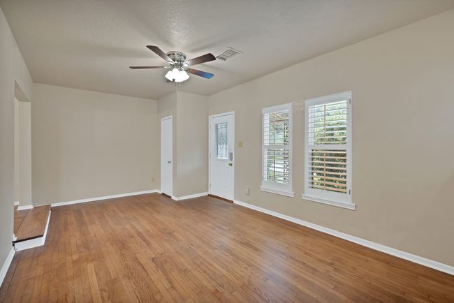 Different angle of Livingroom featuring original hardwood flooring, a ceiling fan, and plantation shutters | Image 11