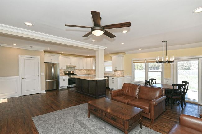 Living area with recessed lighting, crown molding, dark wood-style floors, and ceiling fan with notable chandelier | Image 21