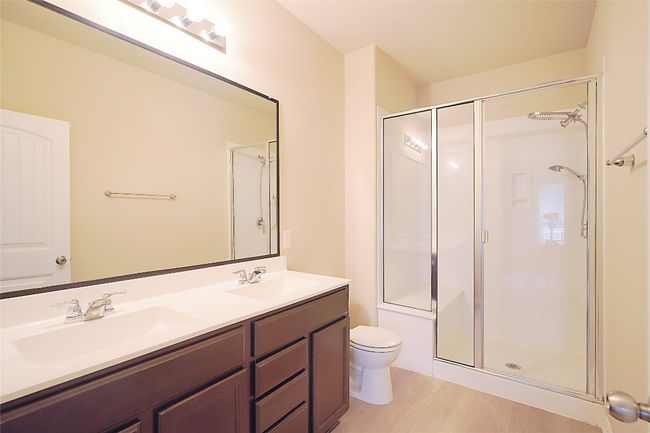 Bathroom featuring double vanity, a shower stall, and wood finished floors | Image 9