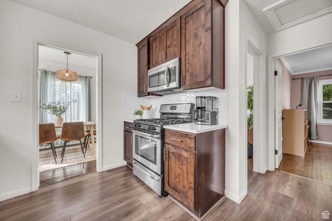 Kitchen featuring stainless steel appliances, dark wood-type flooring, light countertops, and baseboards | Image 7