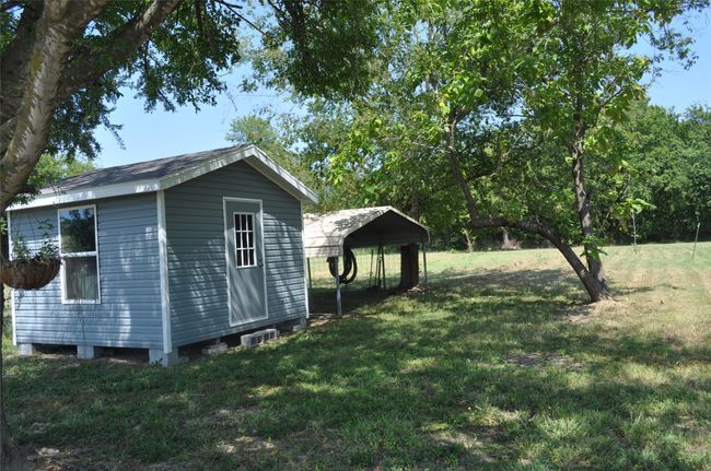 View of yard featuring a carport and a storage unit | Image 12