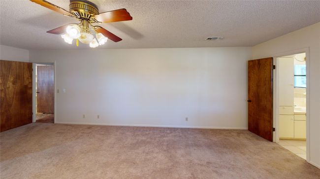 Unfurnished room featuring light colored carpet, a textured ceiling, ceiling fan, and baseboards | Image 16