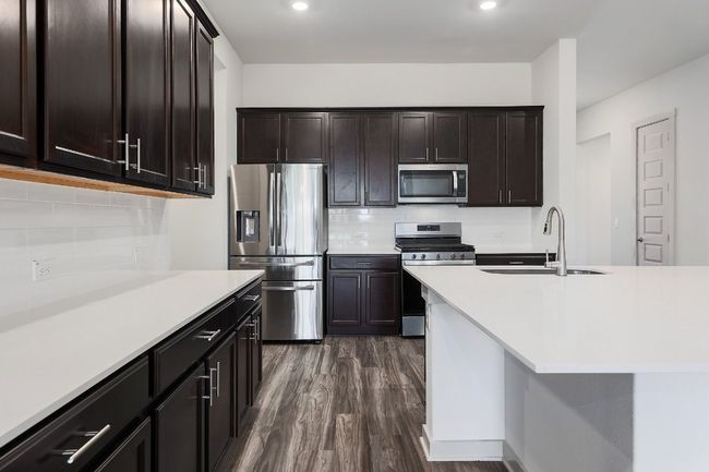 Kitchen with appliances with stainless steel finishes, recessed lighting, light countertops, light wood-style floors, and dark brown cabinetry | Image 10