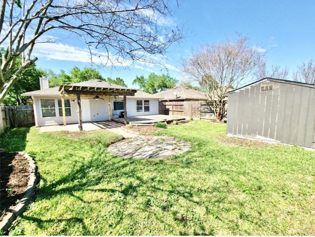 Back of property featuring a chimney, a fenced backyard, a ceiling fan, a patio, and a storage shed | Image 24