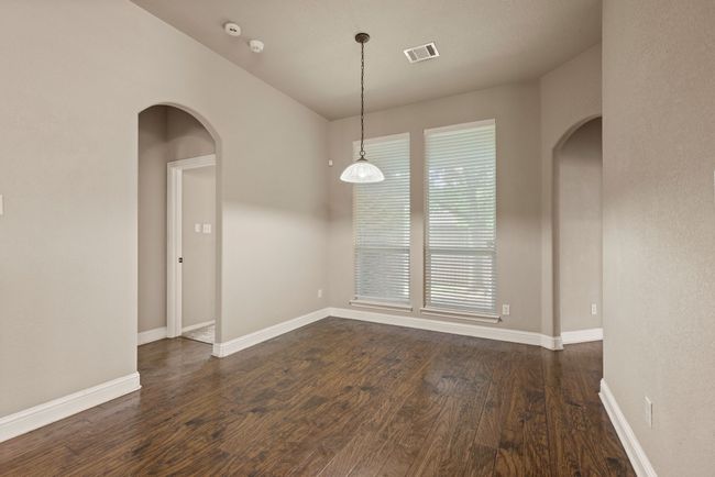 Unfurnished dining area featuring dark wood finished floors, arched walkways, visible vents, and baseboards | Image 11