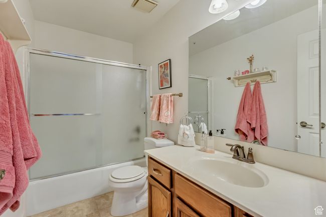 Full bath with tile patterned flooring, visible vents, toilet, vanity, and bath / shower combo with glass door | Image 19
