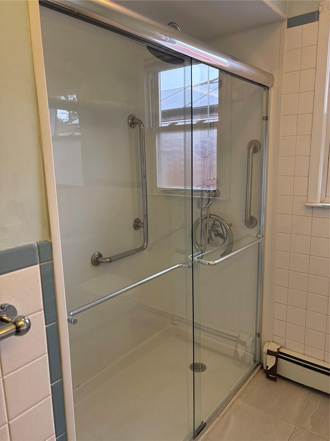 Bathroom with tile walls, a stall shower, and a baseboard radiator | Image 5