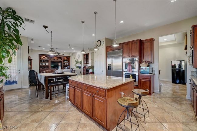 Kitchen with appliances with stainless steel finishes, recessed lighting, a kitchen island, pendant lighting, and light stone countertops | Image 15