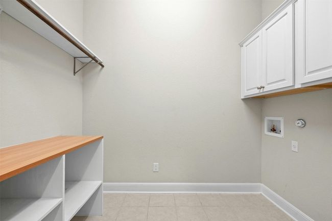 The well-designed laundry room features ample storage with built-in cabinetry and shelving, keeping essentials neatly organized. | Image 27