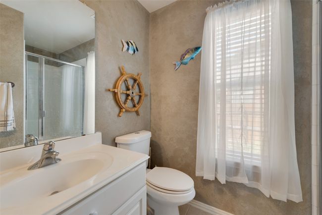 Full downstairs bathroom featuring toilet, a shower stall, and vanity | Image 15