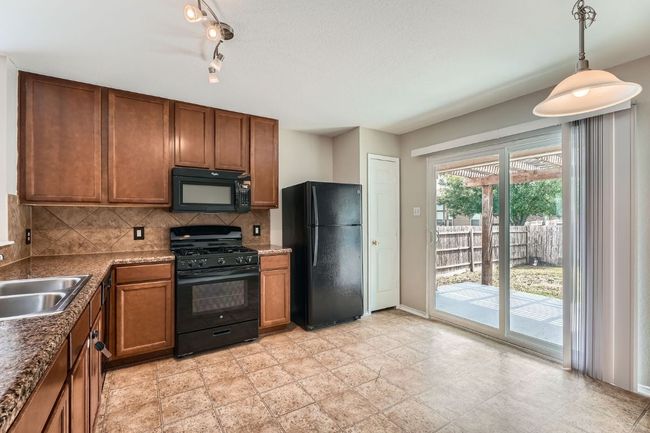 Kitchen featuring black appliances, a sink, brown cabinetry, and tasteful backsplash | Image 4
