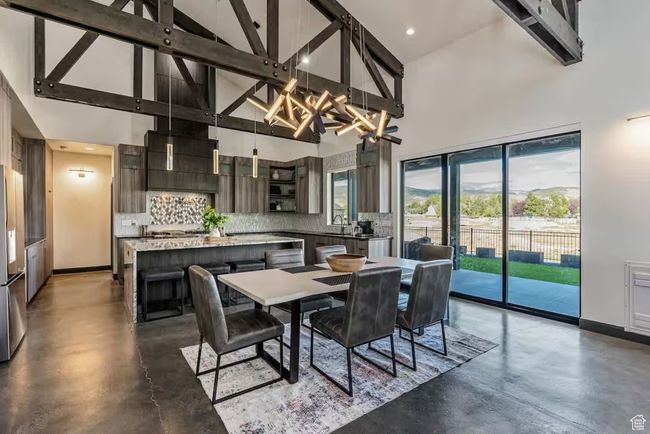 Dining space featuring an inviting chandelier, concrete floors, baseboards, and high vaulted ceiling | Image 8