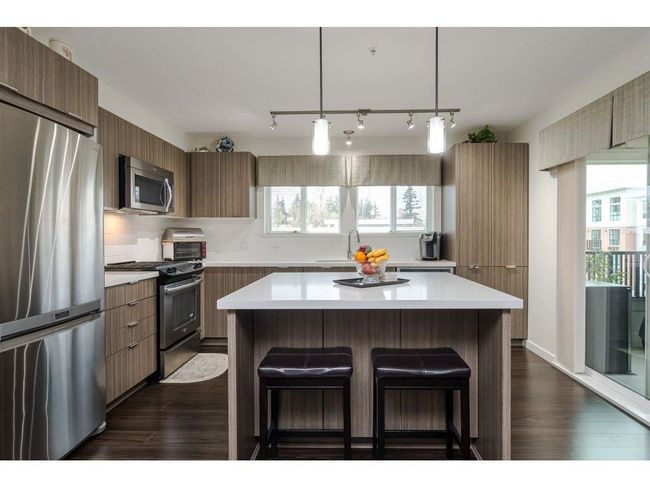 Kitchen with tasteful backsplash, a breakfast bar area, stainless steel appliances, light countertops, and dark wood-style flooring | Image 7