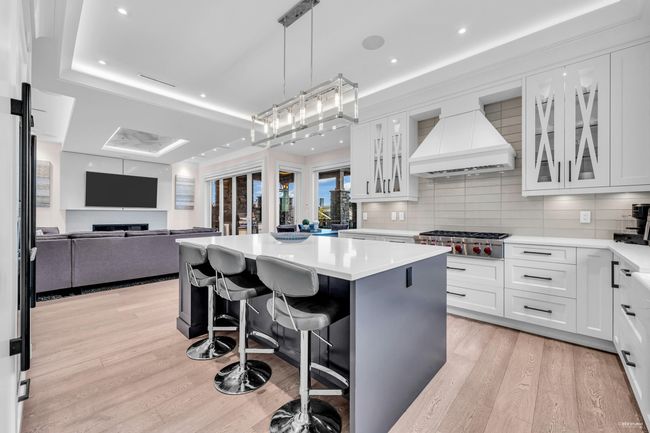 Kitchen with a center island, a kitchen bar, stainless steel gas cooktop, light wood finished floors, and premium range hood | Image 8