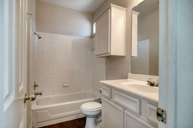 Full bathroom featuring toilet, vanity, wood finished floors, and washtub / shower combination | Image 9