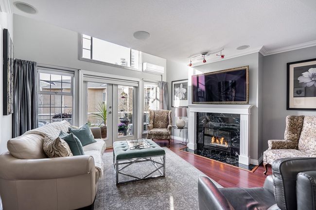 Living area with ornamental molding, wood finished floors, a wealth of natural light, and a premium fireplace | Image 10