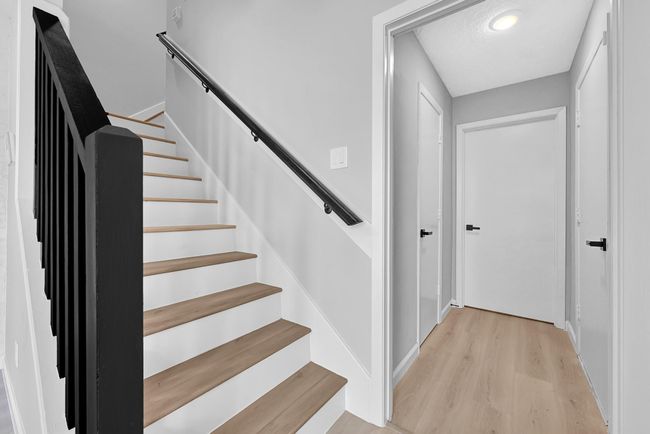 Sleek and modern staircase with fresh paint, updated railing, and new wood treads—leading to spacious upstairs bedrooms. Stylish matte black hardware continues the home's contemporary design theme. | Image 35