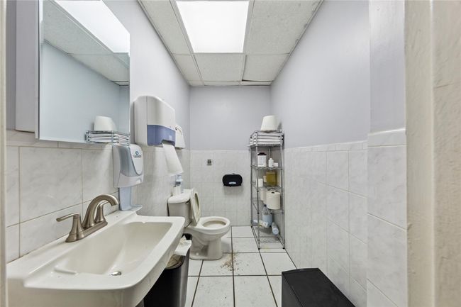 Bathroom featuring sink, a paneled ceiling, tile walls, tile patterned floors, and toilet | Image 43