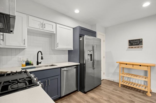 Kitchen with appliances with stainless steel finishes, light countertops, white cabinets, decorative backsplash, and recessed lighting | Image 12