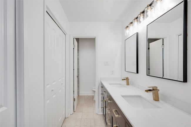 Full bath with double vanity, toilet, baseboards, and a sink | Image 24