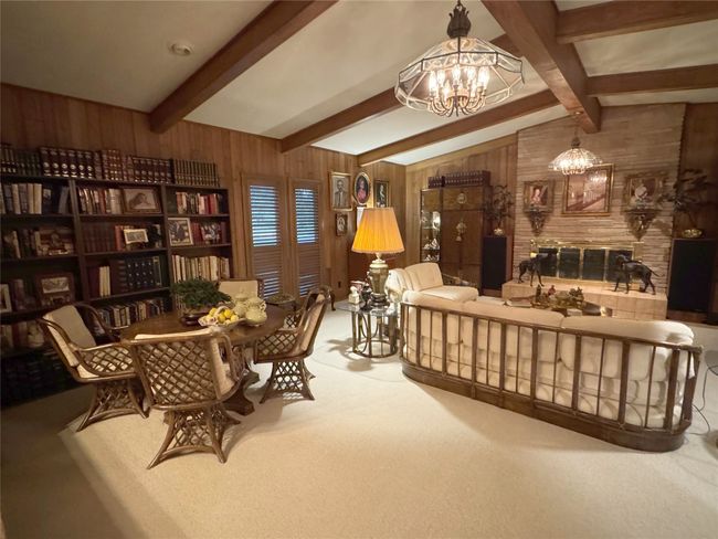 Living area featuring a chandelier, wooden walls, and carpet | Image 18