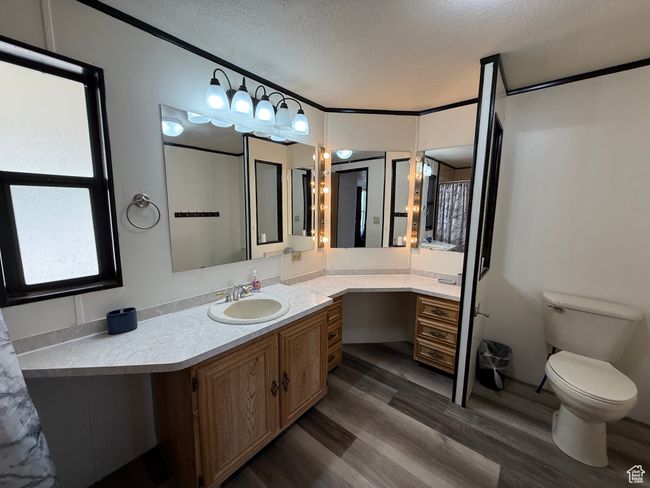 Full bathroom featuring a textured ceiling, wood finished floors, vanity, and toilet | Image 8