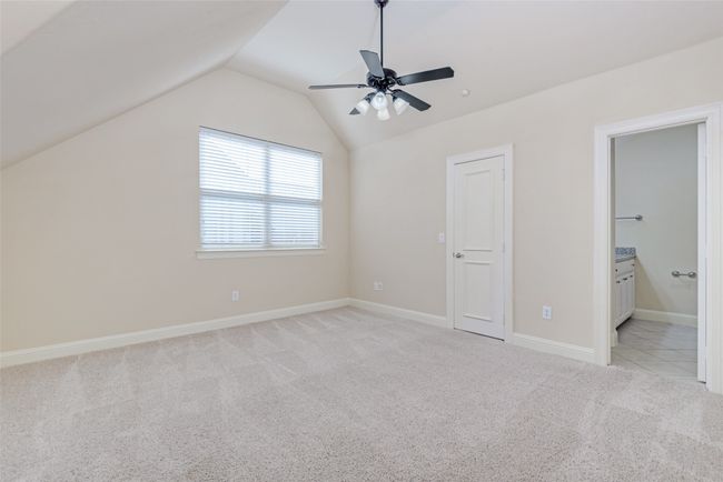 Unfurnished bedroom with carpet, vaulted ceiling, connected bathroom, and a ceiling fan | Image 11