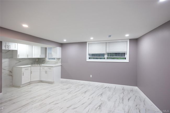 Kitchen featuring white cabinetry, recessed lighting, light marble finish flooring, backsplash, and light stone counters | Image 26
